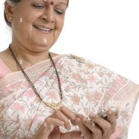Old lady dialing mobile and smiling wearing saree Mangalsutra diamond nose stud or ring Kumkum Stock Photo